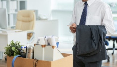 unrecognizable-man-standing-office-using-smartphone-with-personal-belongings-box